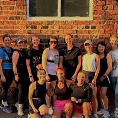 Run club group smiling outside the gym in the evening sun